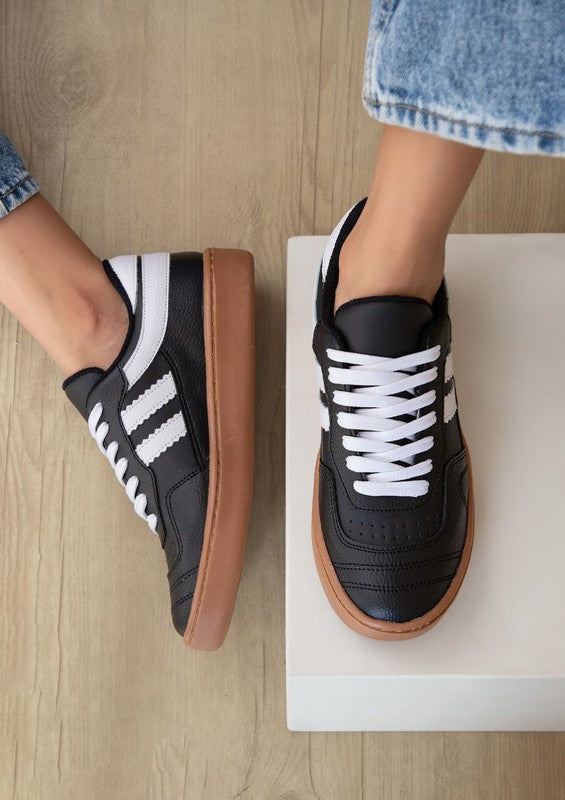 Black leather shoes with white accents and brown sole