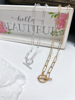 Close up of paper clip long chain necklace in silver and gold toggle closure
