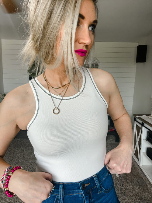 white form fitted bodysuit with black trim stitching 
