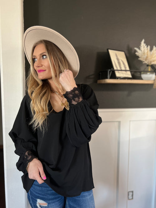Black V-neck blouse with bishop sleeves and wrist lace trim